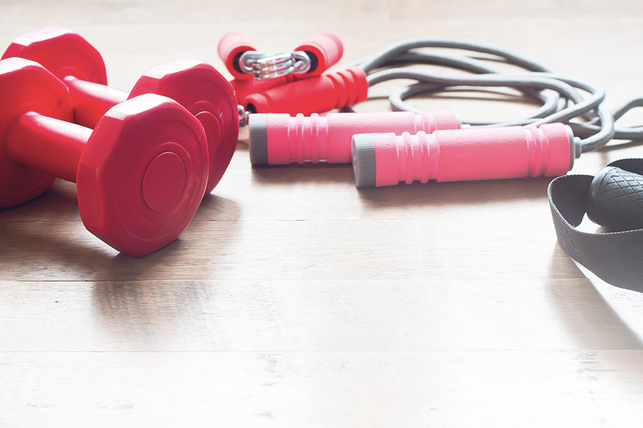 Functional Therapeutics Swfl - A set of dumbbells and a band used in exercise prescription on a wooden floor.